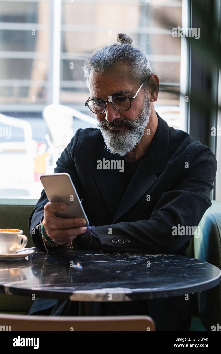 Businessman using mobile phone while sitting at cafe Stock Photo
