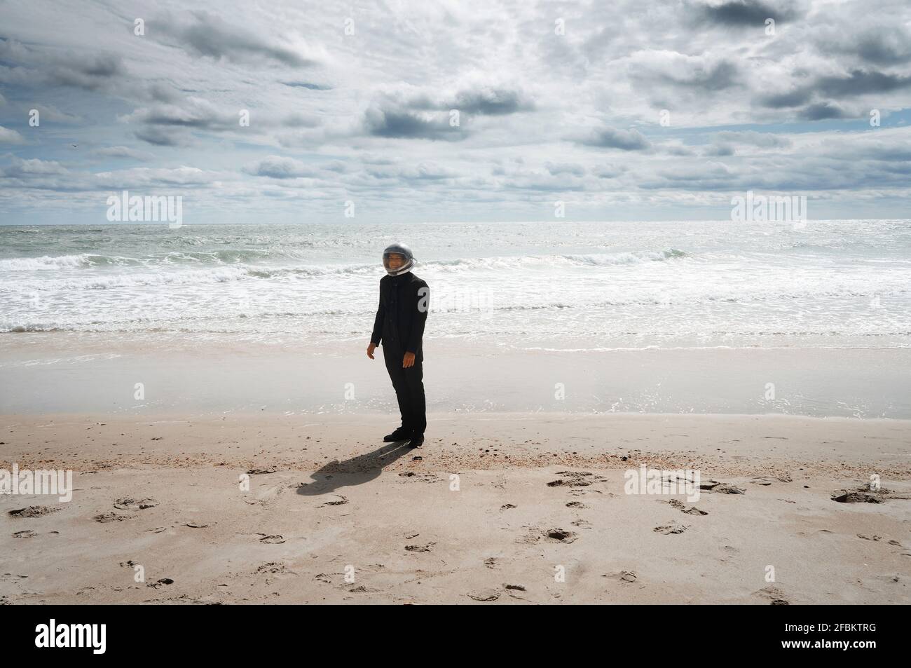 Astronautic man wearing space helmet while standing on sea shore Stock Photo