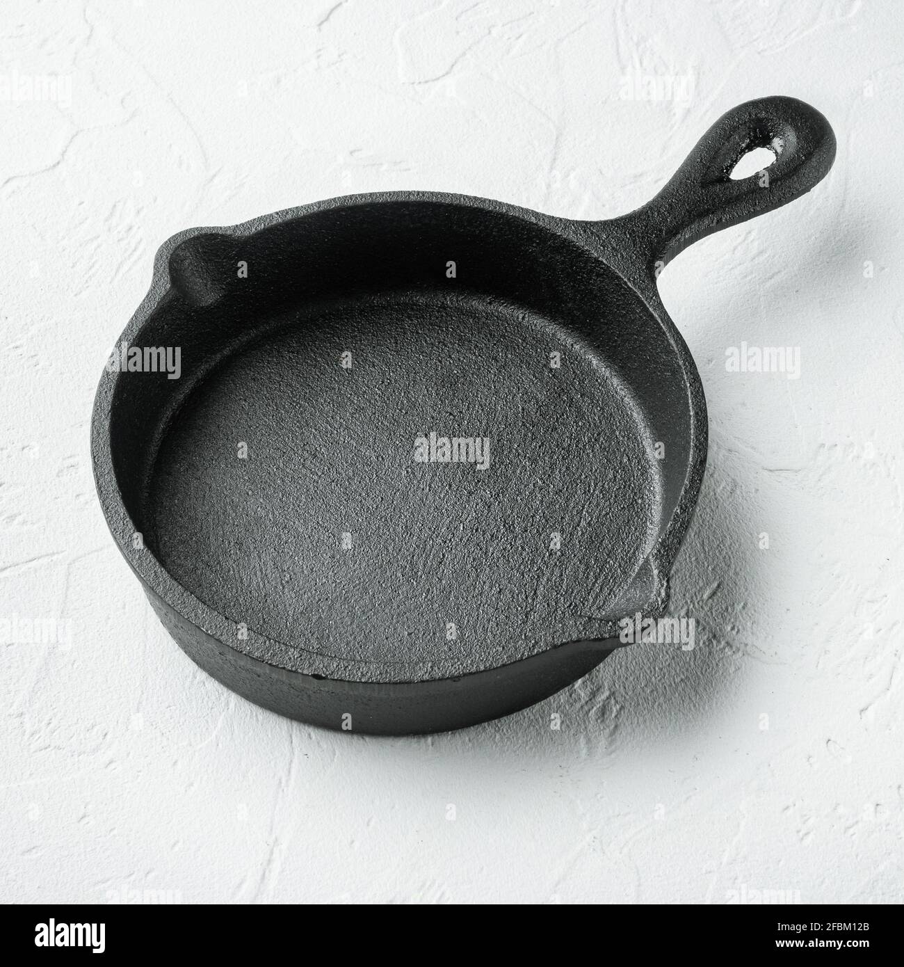 Kitchenware frying, cast iron pan, on white stone surface, square format Stock Photo