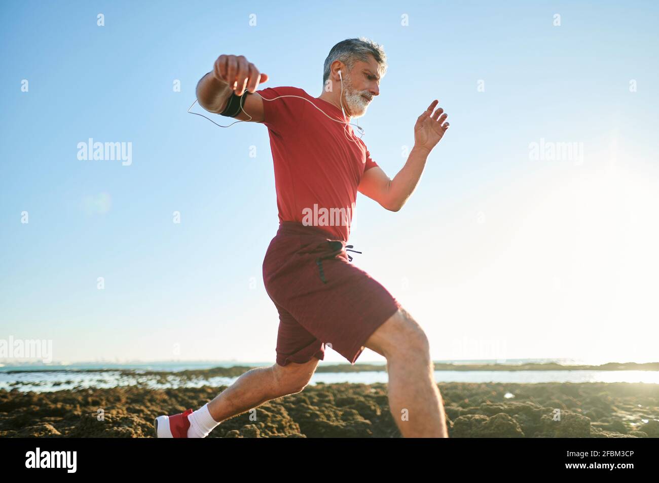 Male jogger running on rocks at beach Stock Photo Alamy