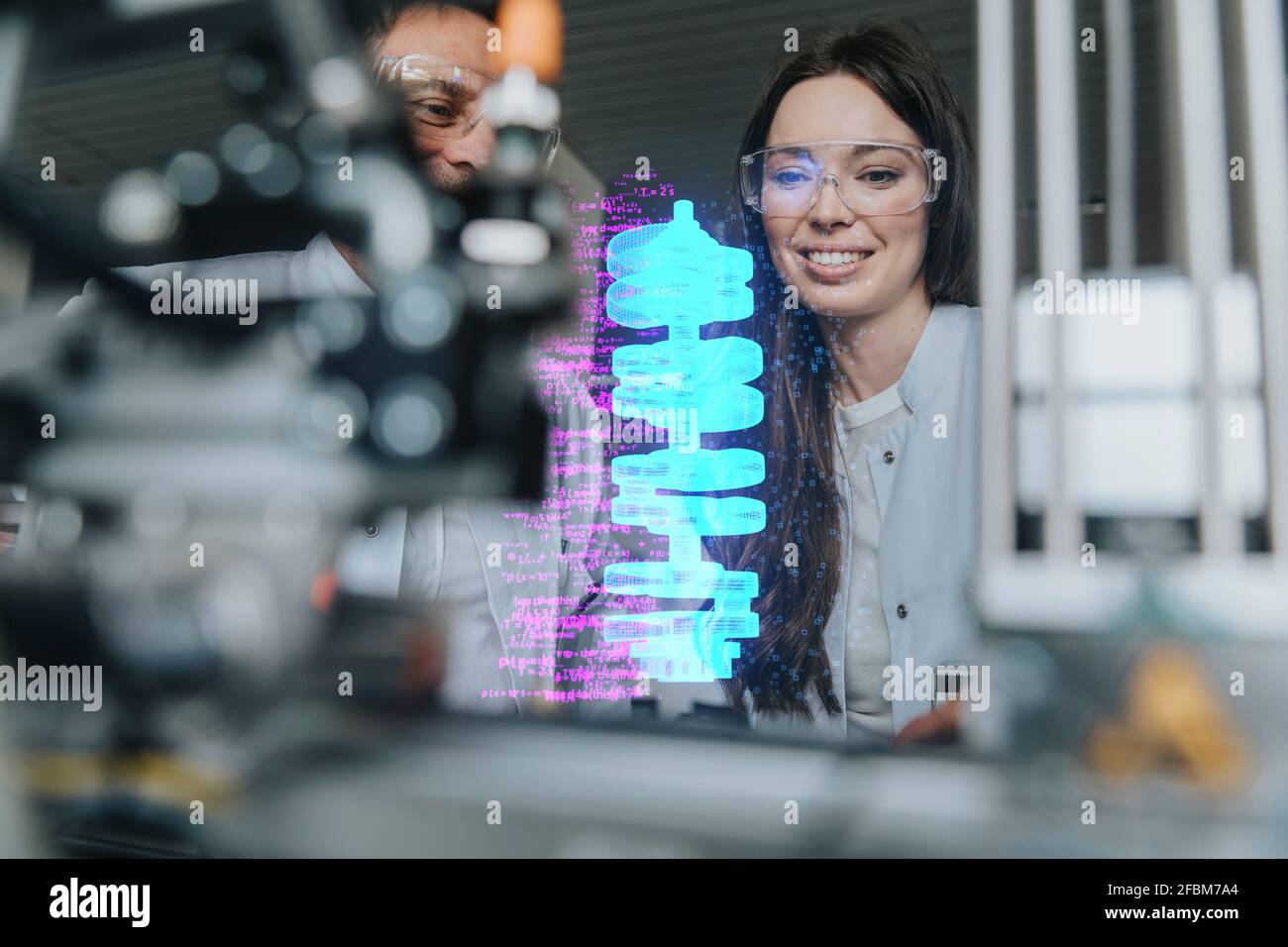 Smiling female and male engineers examining futuristic automation at laboratory Stock Photo