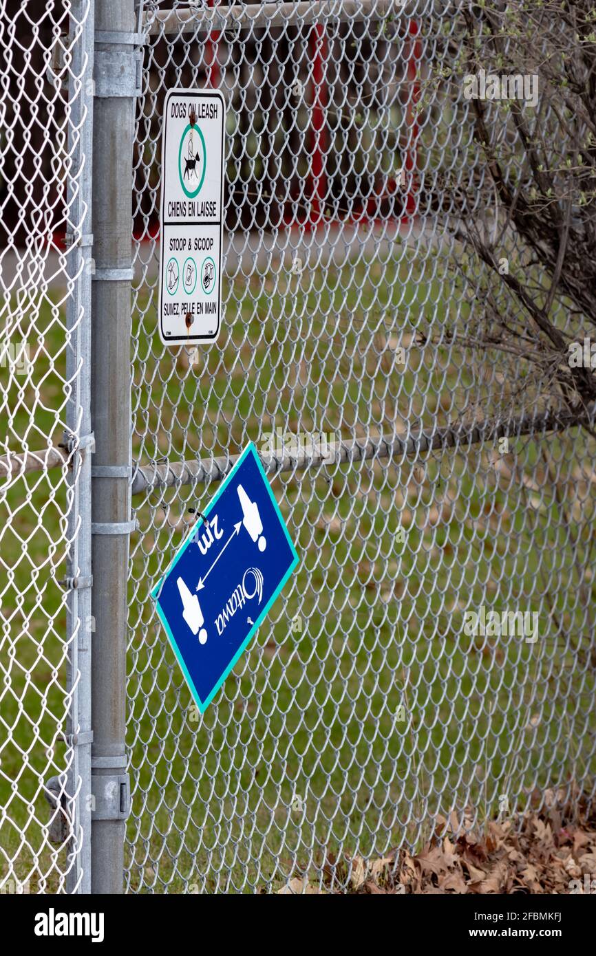 Ottawa, Ontario, Canada - April 17, 2021: A City of Ottawa physical distancing sign on a fence at the Nepean Sportsplex hangs askew as a third wave of Stock Photo