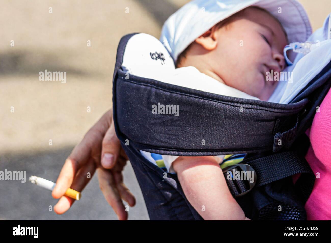 Miami Beach Florida,sleeping baby child mother holding cigarette,smoking secondhand second hand smoke, Stock Photo