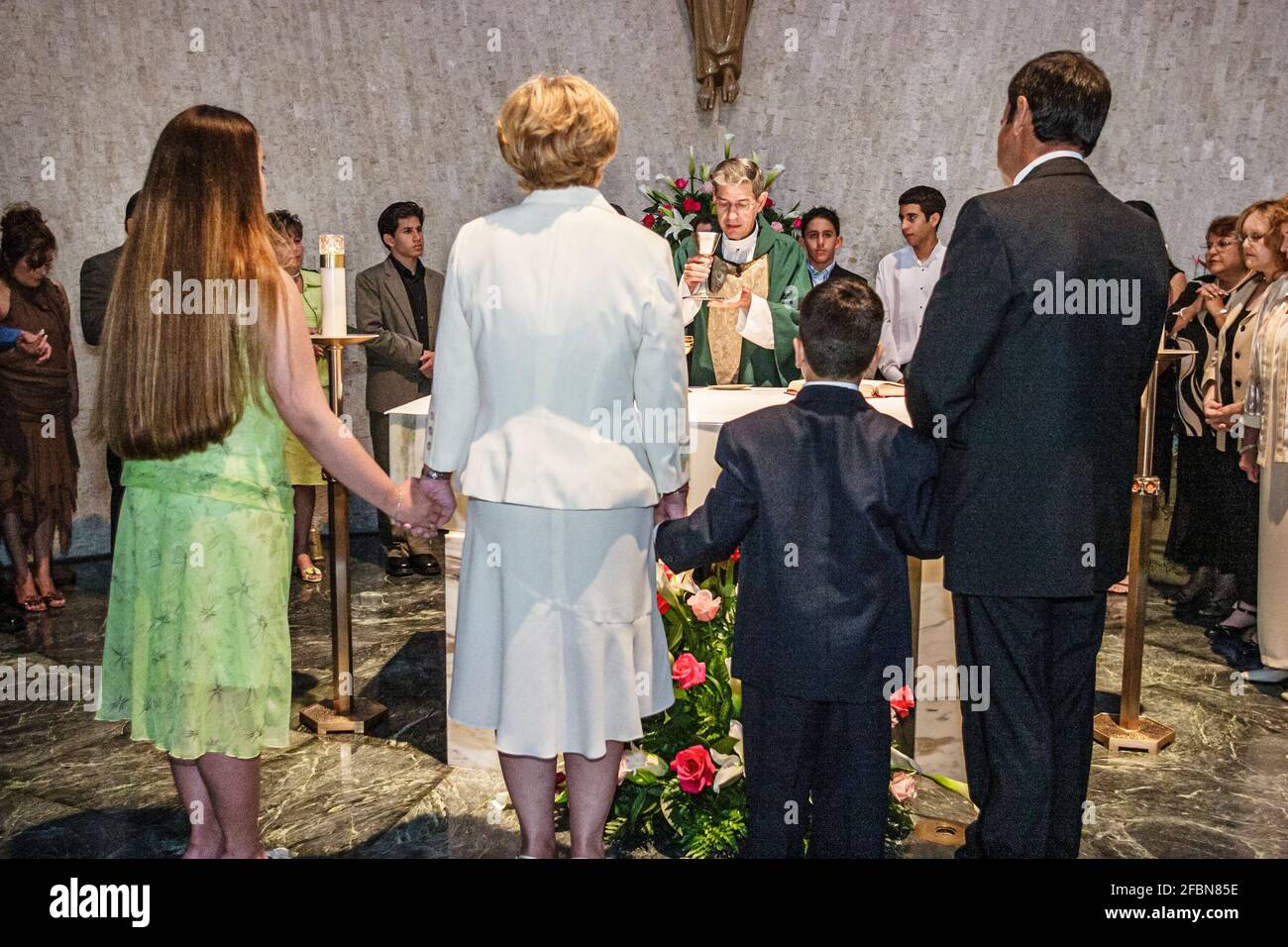 Miami Florida,Hialeah Immaculate Conception Catholic Church,Hispanic congregation altar service priest families parents children holding hands,praying Stock Photo