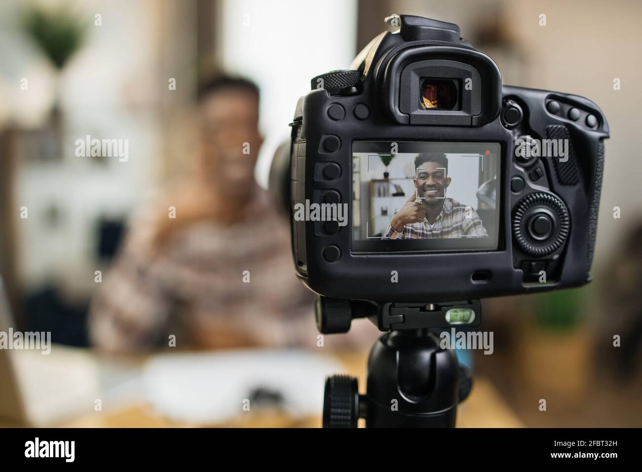 Blur background of smiling black man sitting at table with wireless laptop  and recording video. Focus of modern professional camera. Online tutorial  concept Stock Photo - Alamy