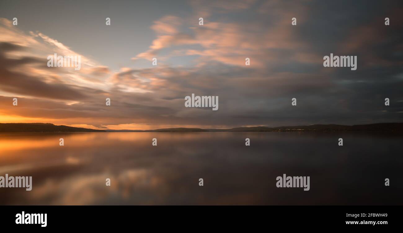 Beautiful sunset over a calm swedish natural lake in late summer photographed with long exposure Stock Photo