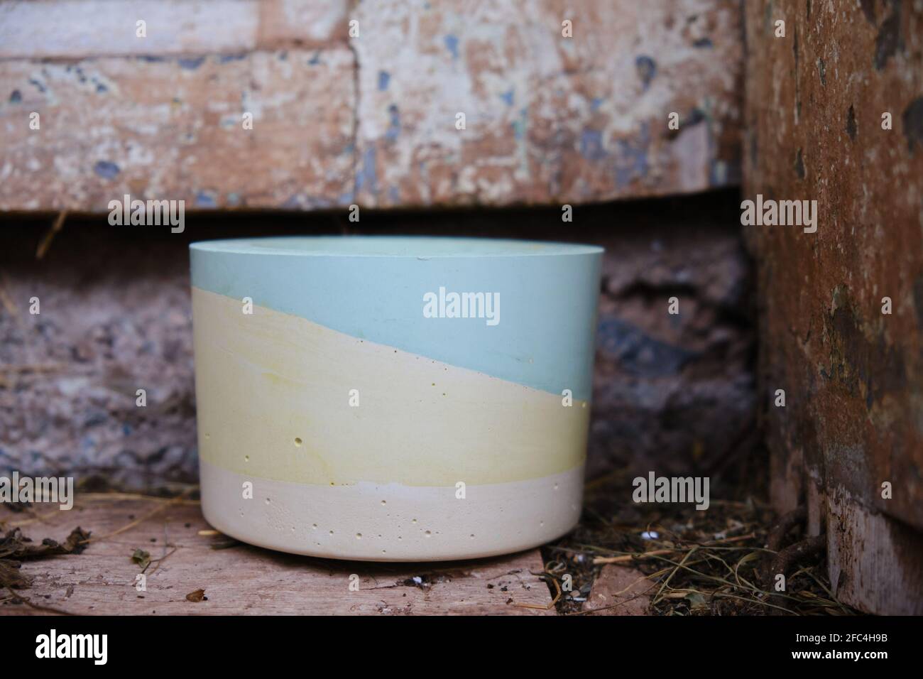 Selective focus on colorful plaster pot for cactuses in front of an old, rustic, wooden door of a house made from mud and some hay on the ground Stock Photo
