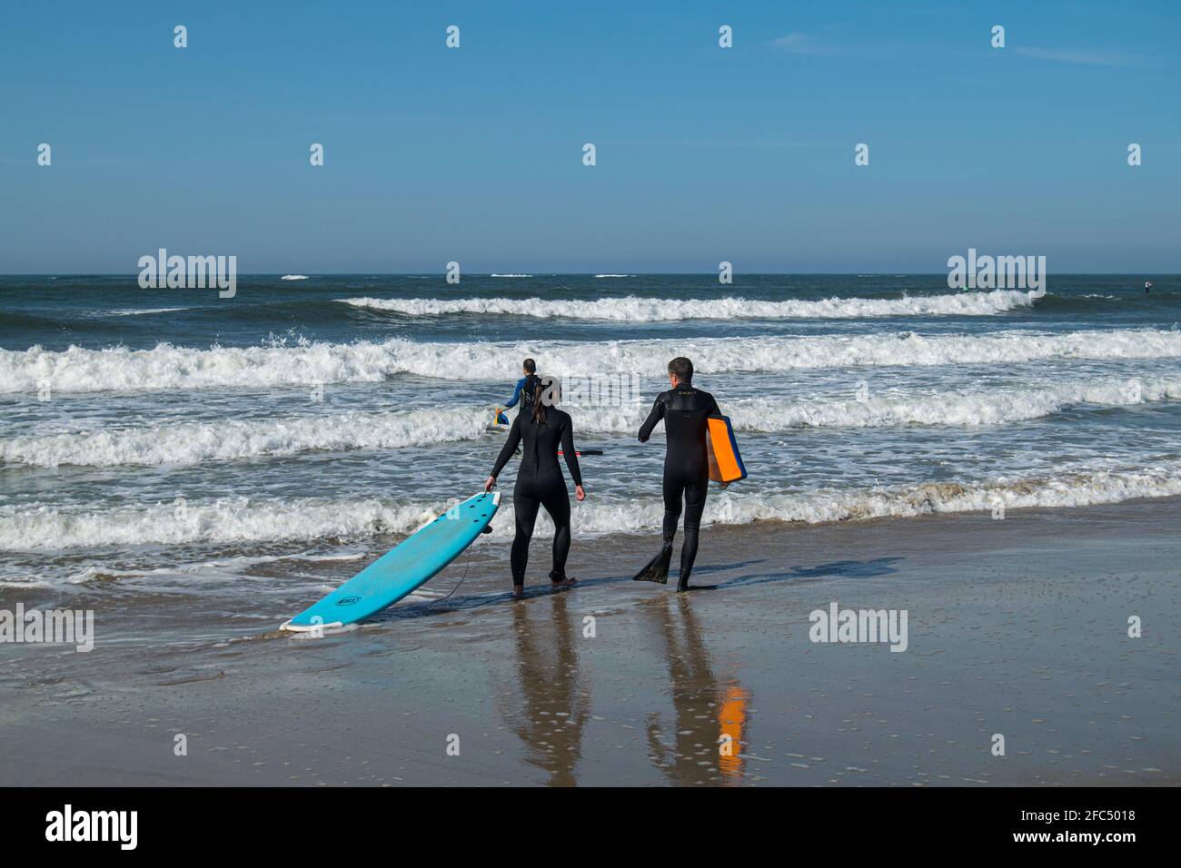Surf trip, couple going to surf and going to practice bodyboard, walking in the beach, surf schools activities. Surf lifestyle. Ocean waves. Stock Photo