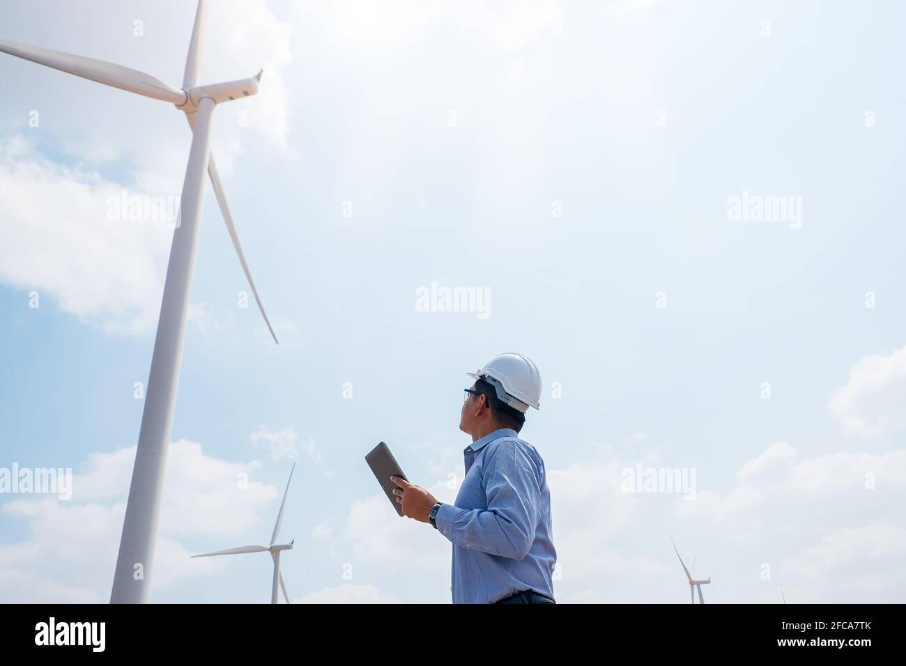 Engineer windmills working on tablet PC with the wind turbine in background Stock Photo