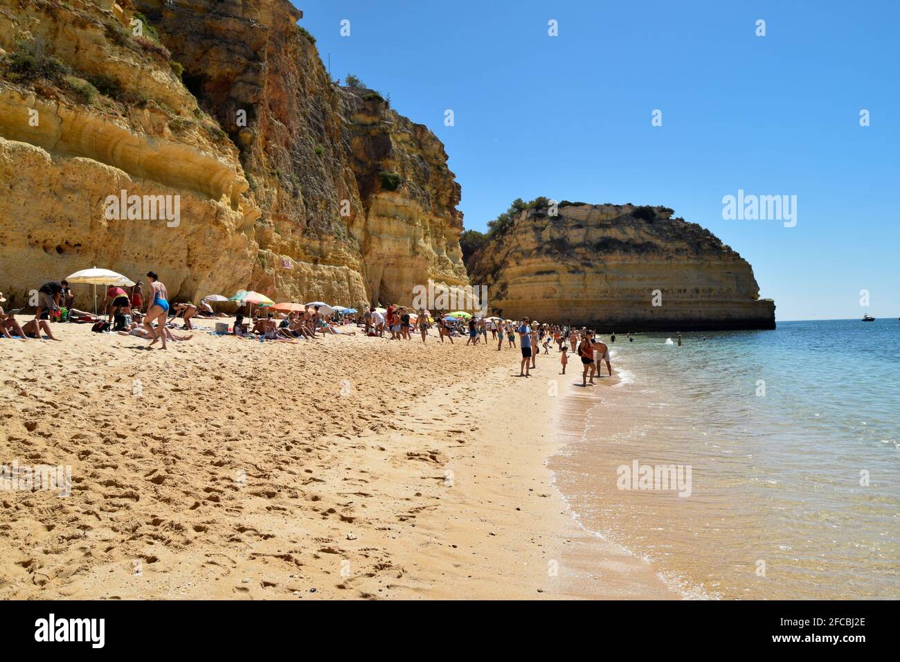 People enjoying the beach at Praia da Marinha, Marinha beach in Algarve Portugal on summer time with beautiful sea and mountains views Stock Photo