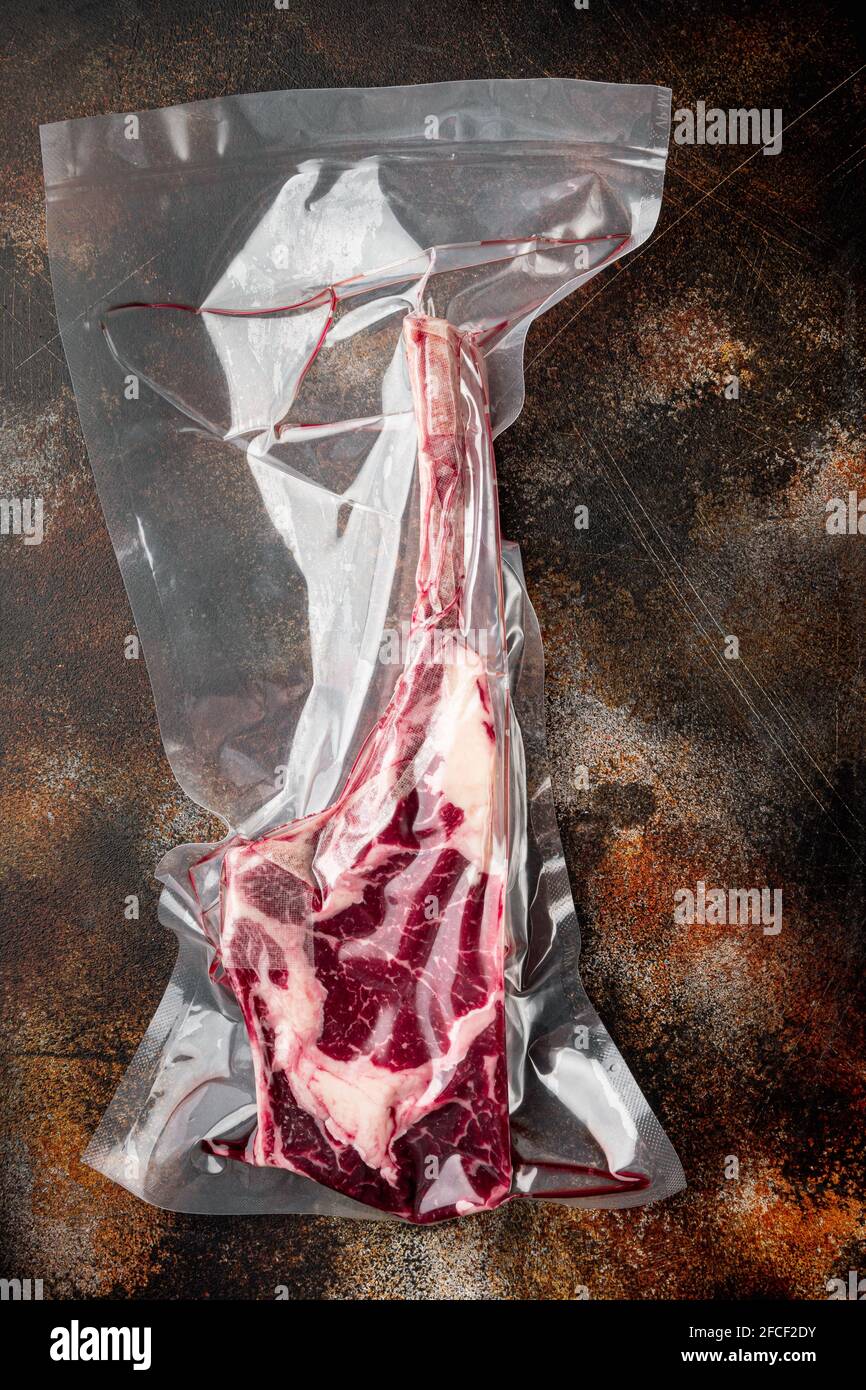 Tomahawk steak vacuum packed dry aged beef marbled meat for sous vide set,  on old dark rustic background, top view flat lay Stock Photo - Alamy