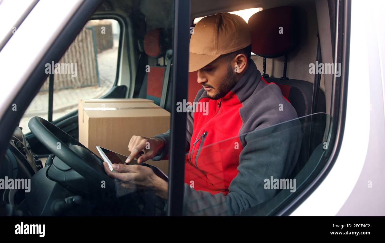 Happy indian courier using tablet in the van . High quality photo Stock Photo