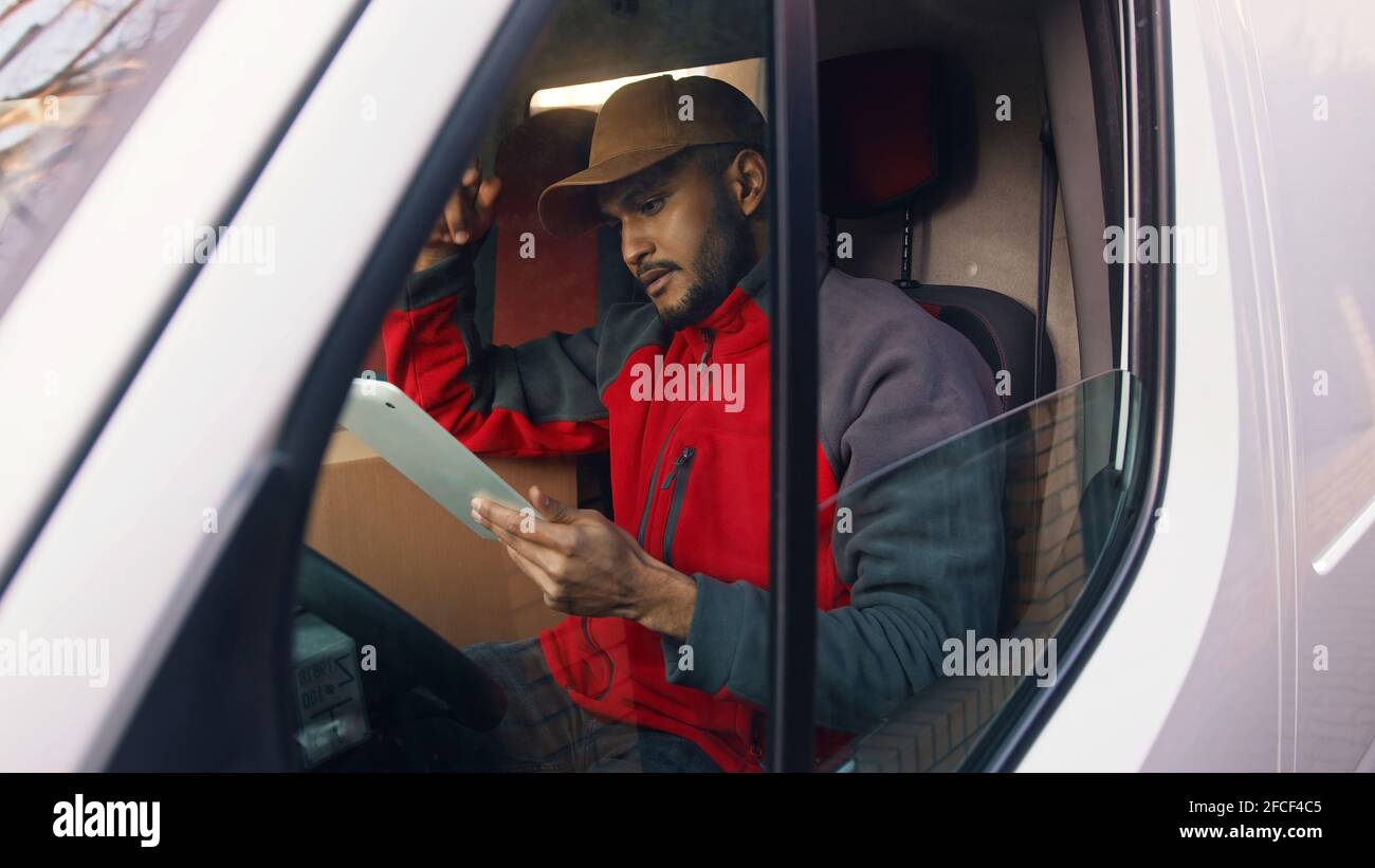 Happy indian courier using tablet in the van . High quality photo Stock Photo
