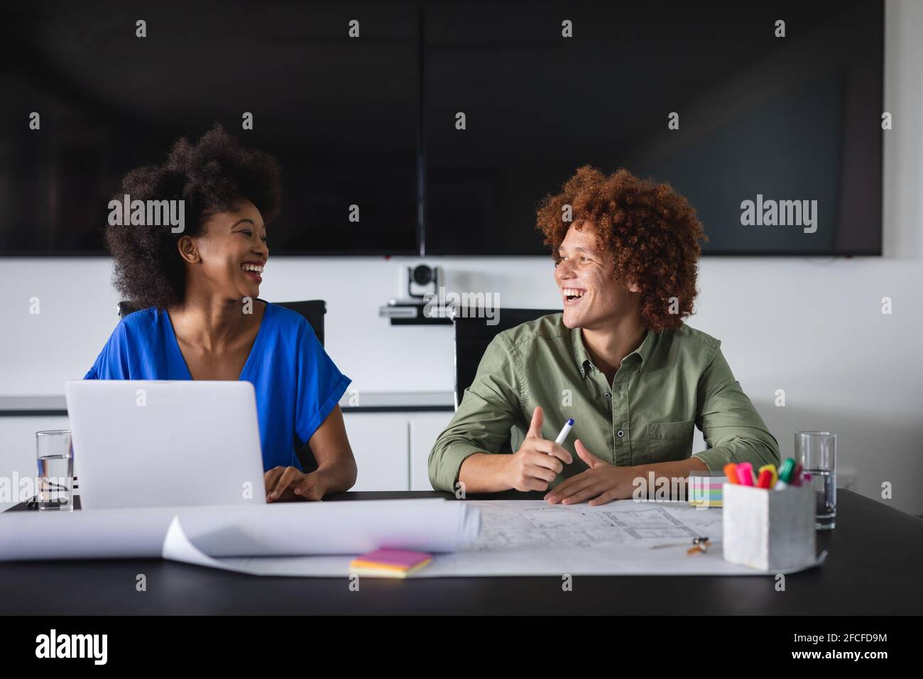 Happy diverse male and female colleagues in office discussing over ...