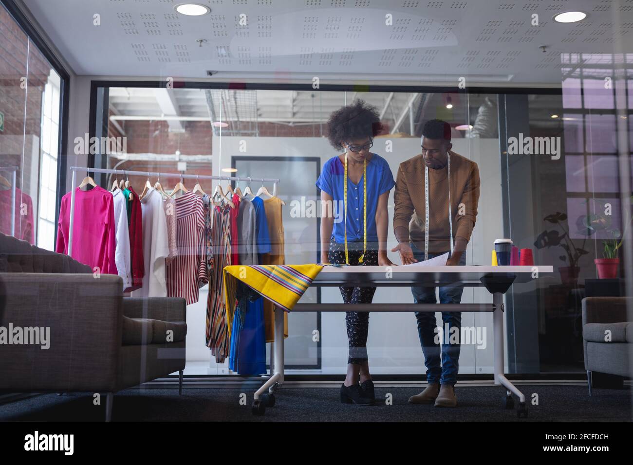 Diverse male and female fashion designers at work discussing and ...