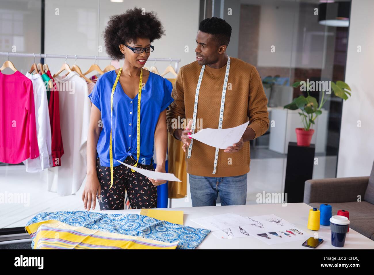 Diverse male and female fashion designers at work discussing and ...