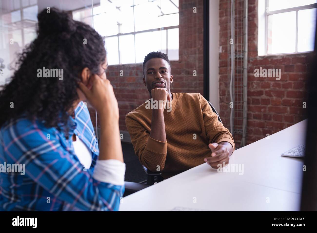 Diverse male and female colleagues sitting at office desk discussing ...