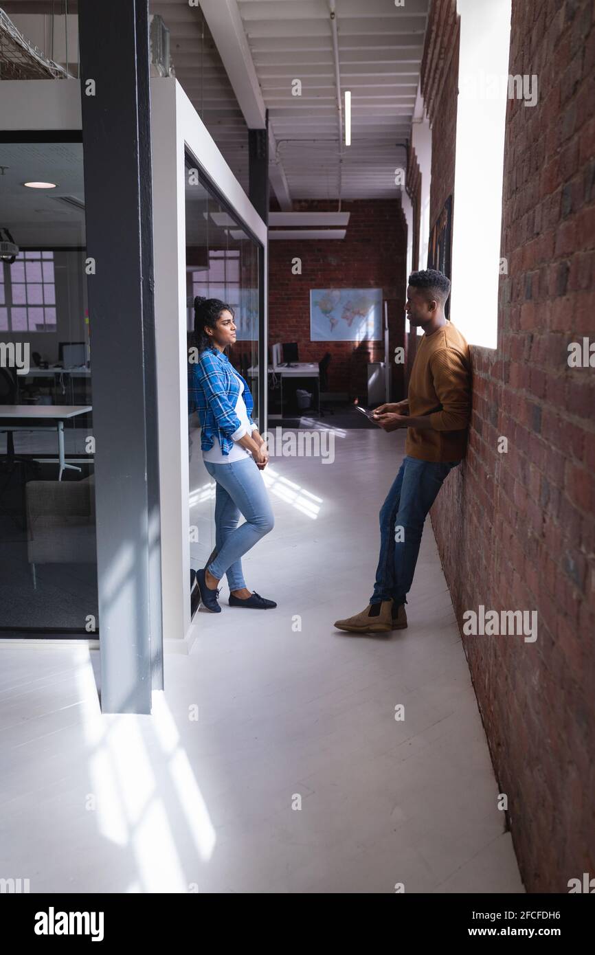 Diverse male and female colleagues at work standing discussing in ...
