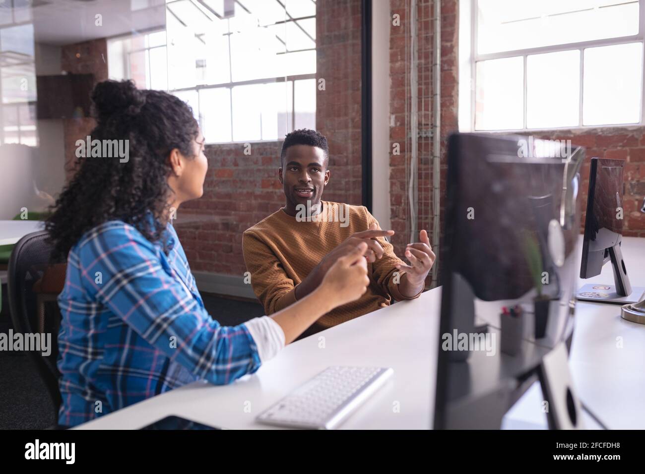 Diverse male and female colleagues at work sitting in front of computer ...