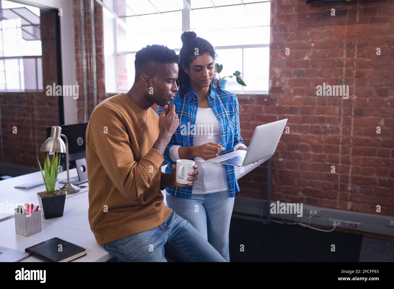 Diverse male and female colleagues at work standing discussing in front ...