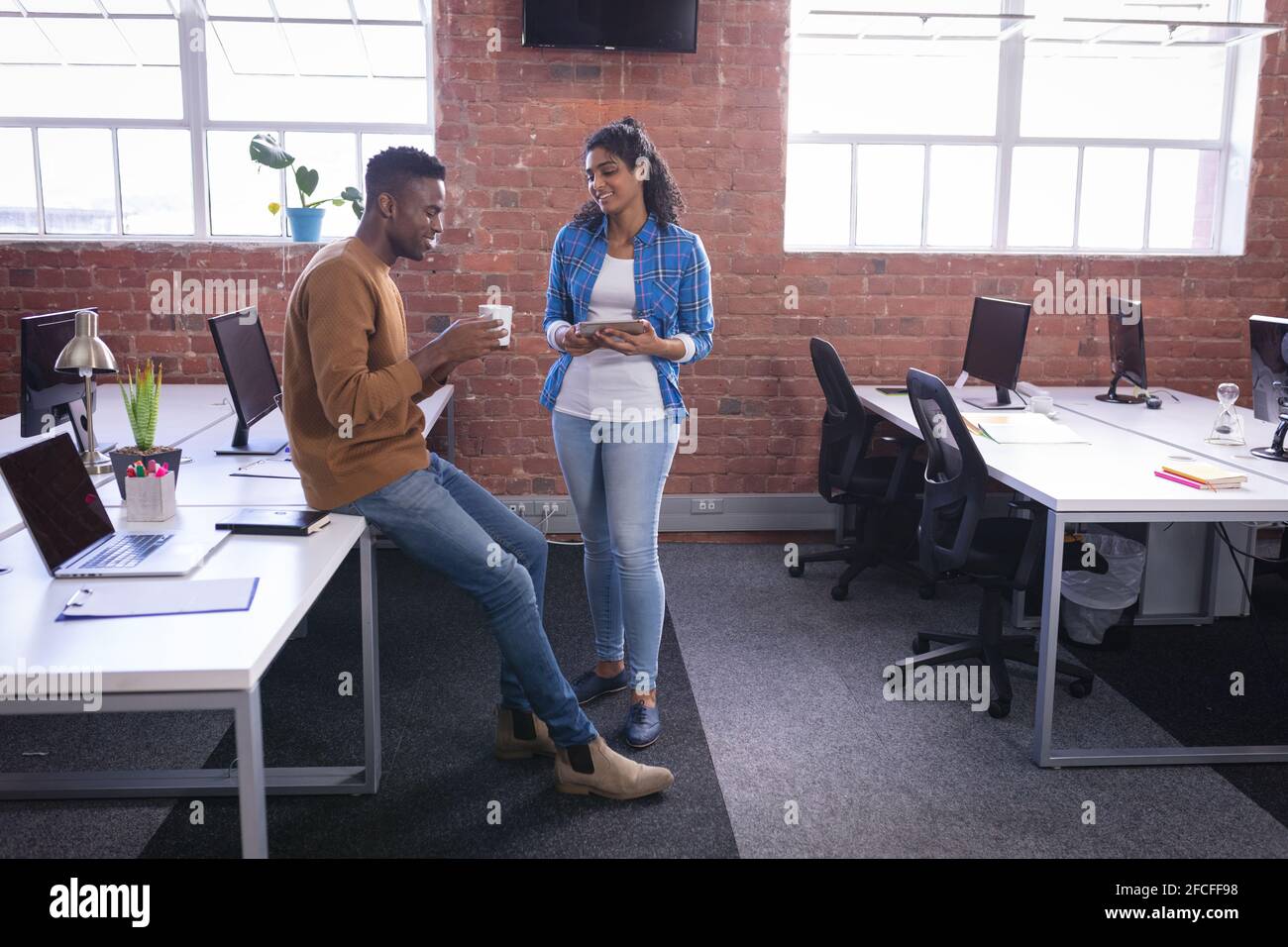 Happy diverse male and female colleagues at work standing discussing ...