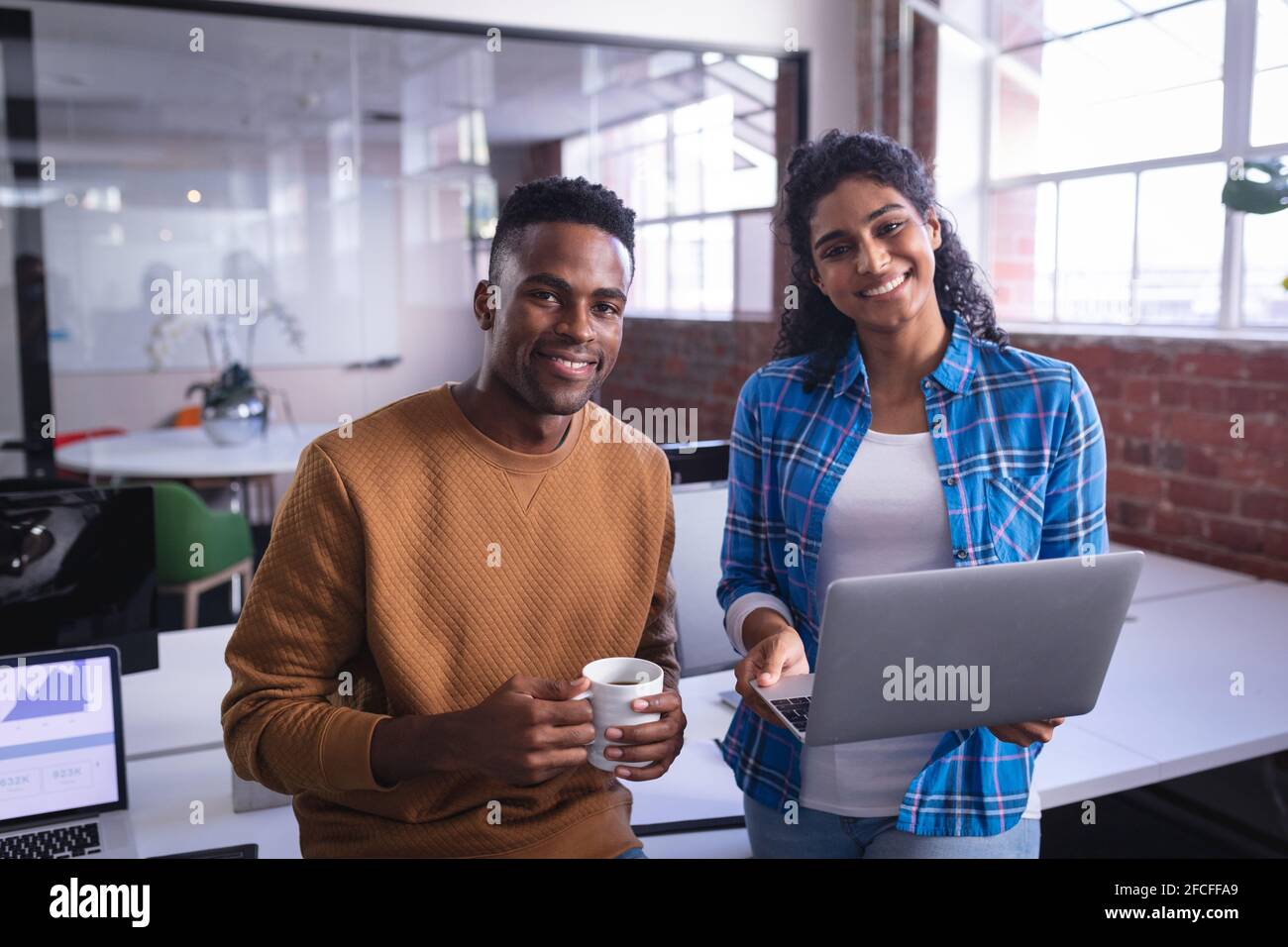 Happy diverse male and female colleagues at work standing discussing in ...