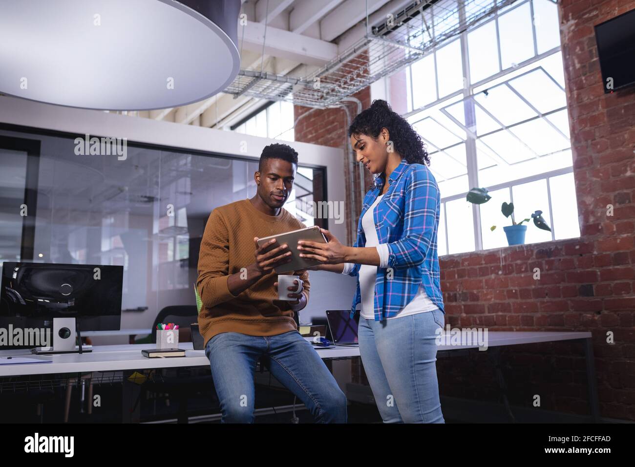 Diverse male and female colleagues at work standing discussing over ...