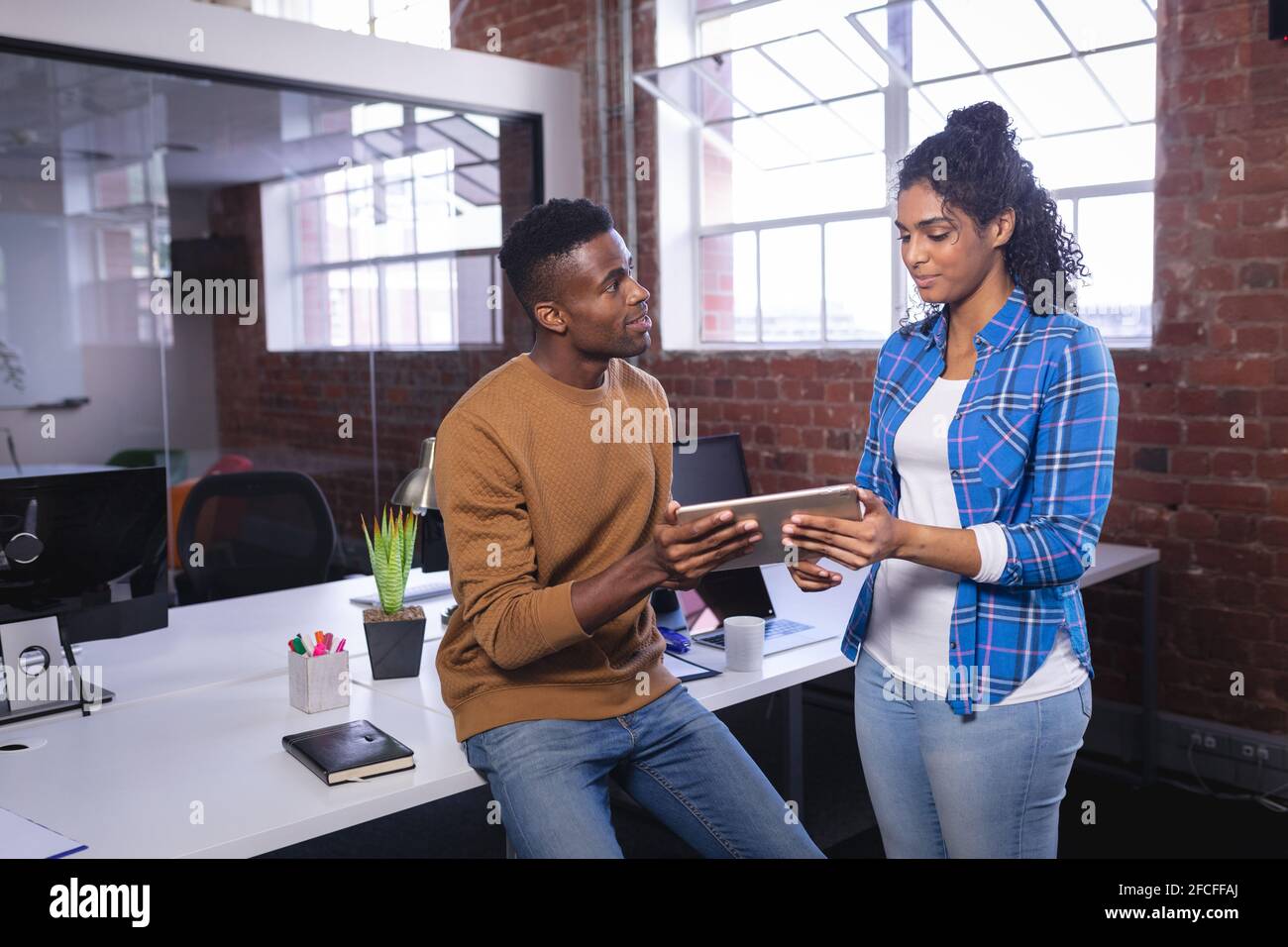 Happy diverse male and female colleagues at work standing discussing ...