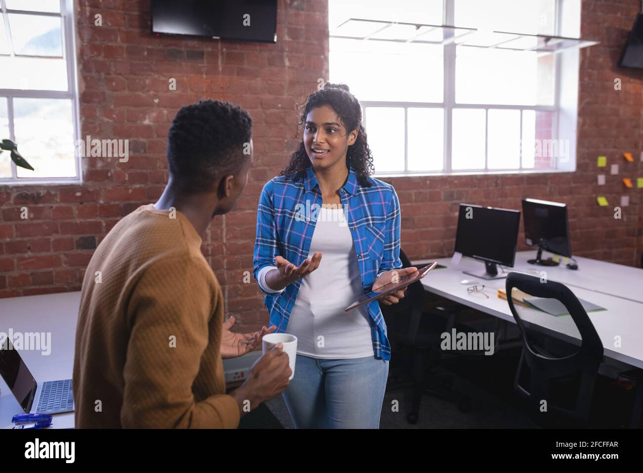 Happy diverse male and female colleagues at work standing discussing ...