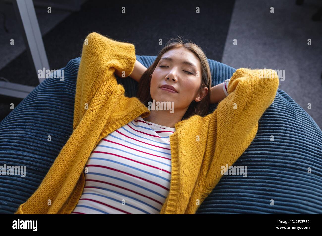 Mixed race businesswoman chilling in office relaxing space lying in beanbag Stock Photo
