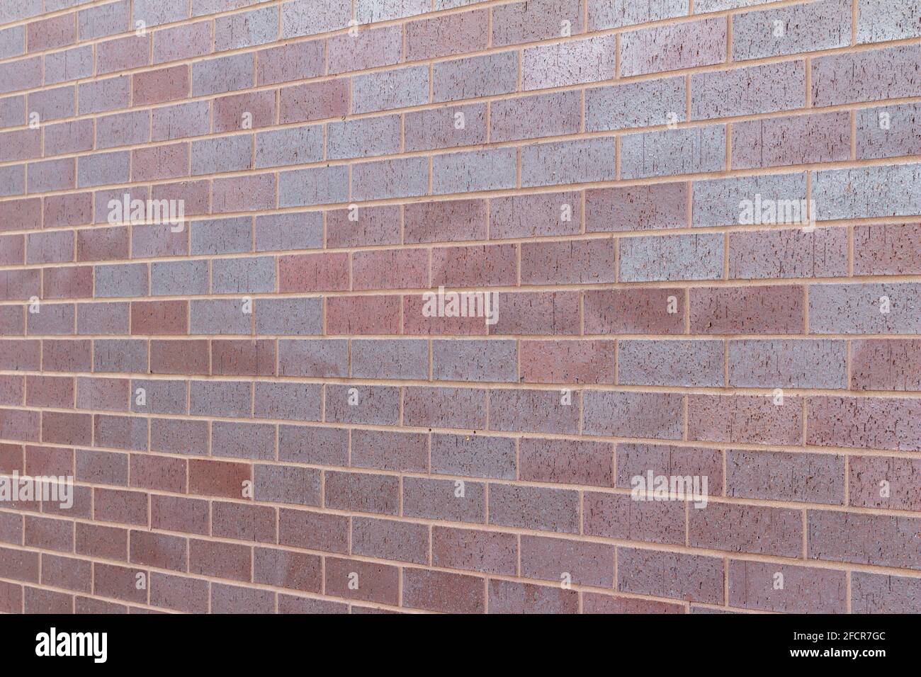 Title Vintage magenta color brick wall texture background in a 1/3 offset stretcher bond pattern, with bricks in varying shades of red and blue Stock Photo