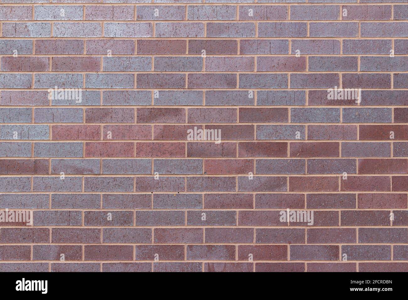 Title Vintage magenta color brick wall texture background in a 1/3 offset stretcher bond pattern, with bricks in varying shades of red and blue Stock Photo