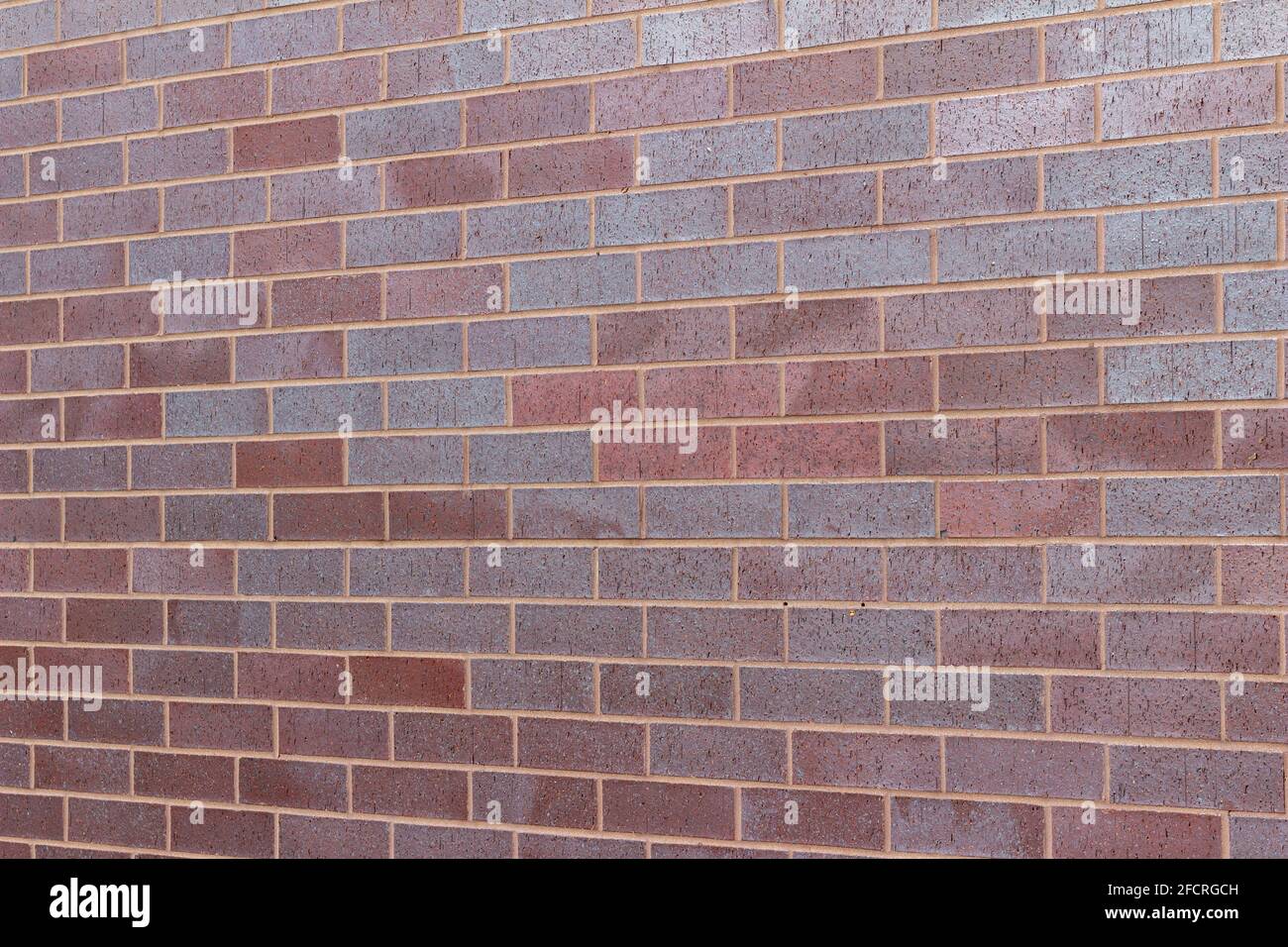 Title Vintage magenta color brick wall texture background in a 1/3 offset stretcher bond pattern, with bricks in varying shades of red and blue Stock Photo