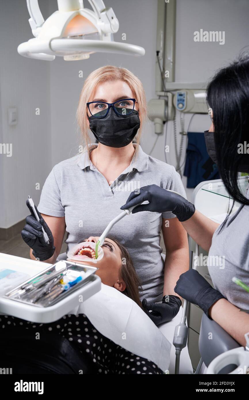 Female dentist and her assistant working together, dental tools in