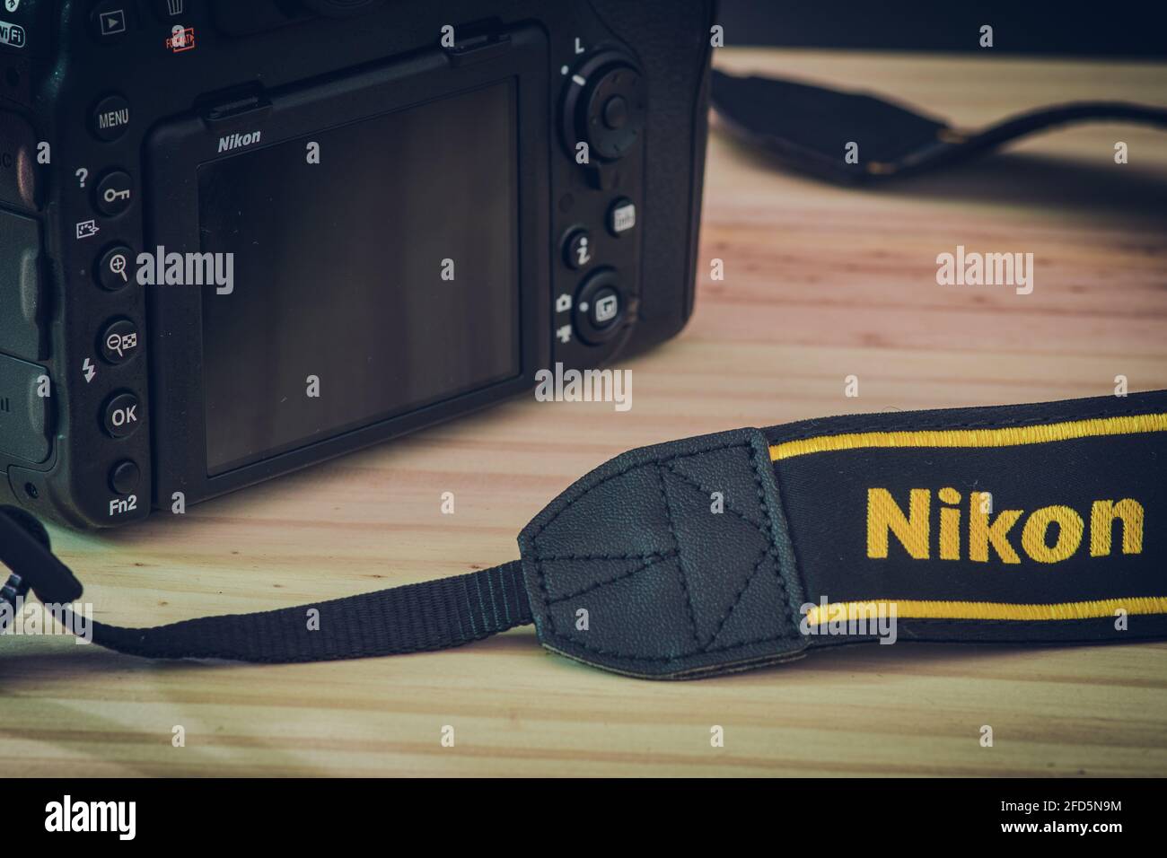 Sri Lanka - 02 17 2021: Modern professional level DSLR body and neck trap with Nikon brand name embraided on a wooden table, Nikon D850 close up photo Stock Photo