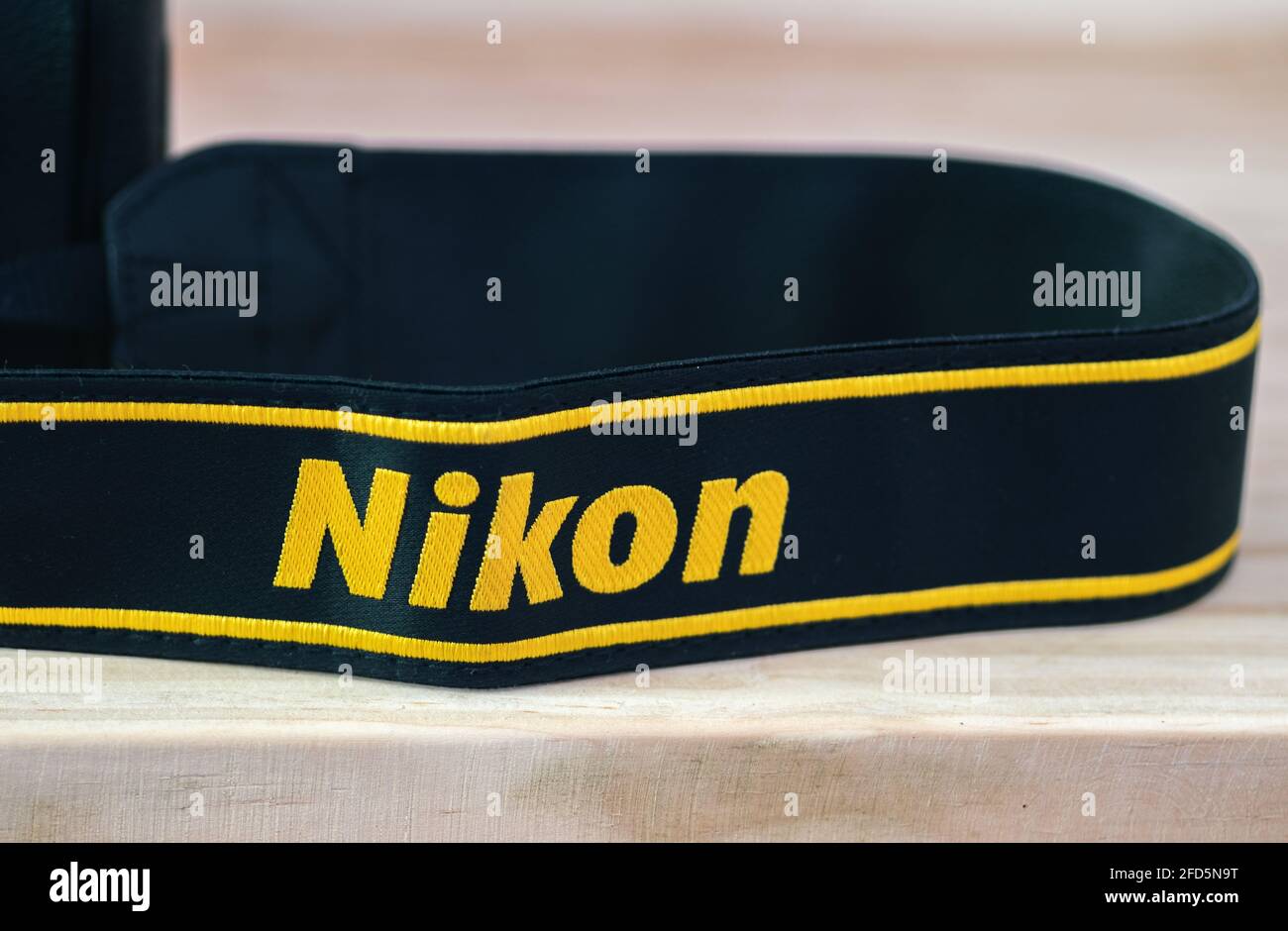 Galle, Sri Lanka - 02 17 2021: Nikon DSLR camera strap on wooden table close up, brand new Nikon logo embroidered in yellow into a black ribbon, profe Stock Photo