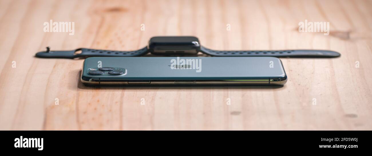 Galle, Sri Lanka - 02 19 2021: Apple iPhone 11 pro max and apple watch series 6 lay flat on a wooden table with low angle side view, luxury and lifest Stock Photo