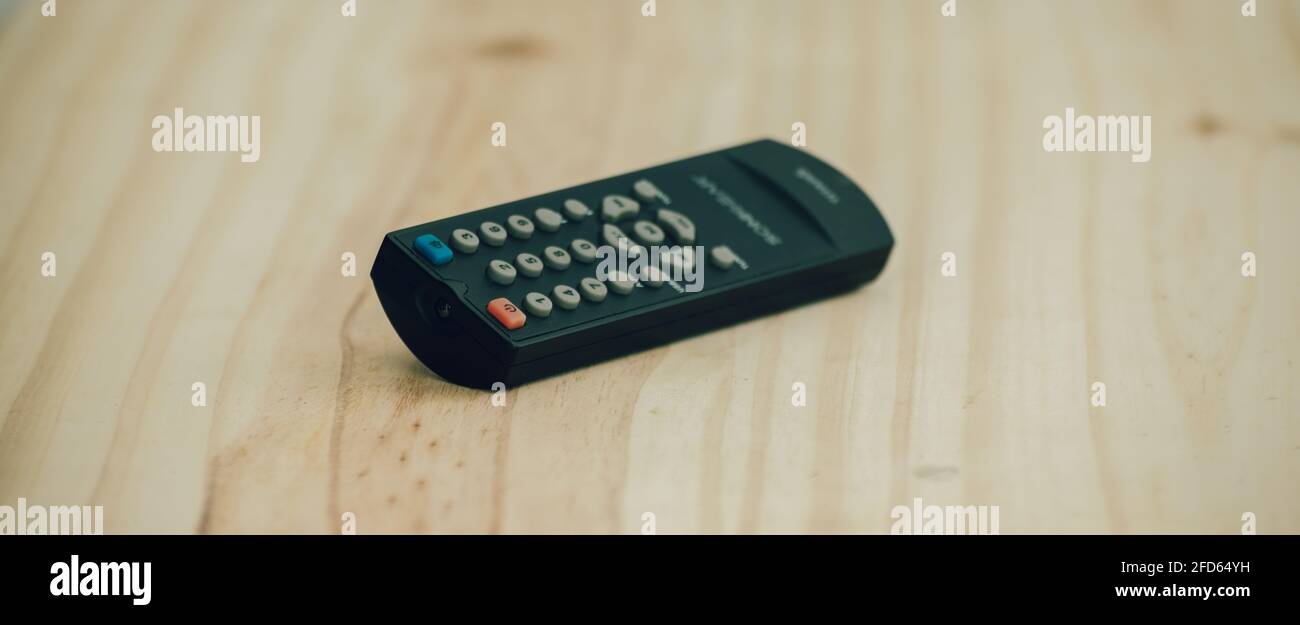 Small Remote controller lay flat on a wooden surface close up photograph. Stock Photo