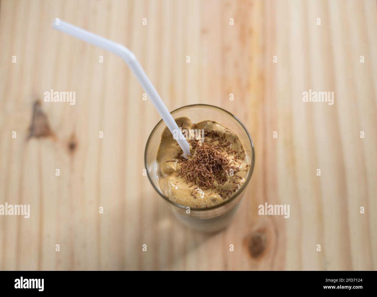 Homemade Dalgona coffee glass in a wooden textured tabletop. whisked instant coffee topping with fresh milk, making the delicious Korean drink. Trendy Stock Photo
