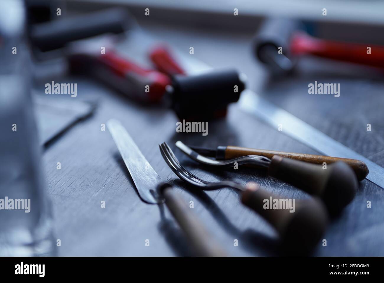 Linocut concept. Working tools in red and black colors on dark table.  Cutting instruments, ink roller and other tools for linocut making. High  quality photo Stock Photo - Alamy