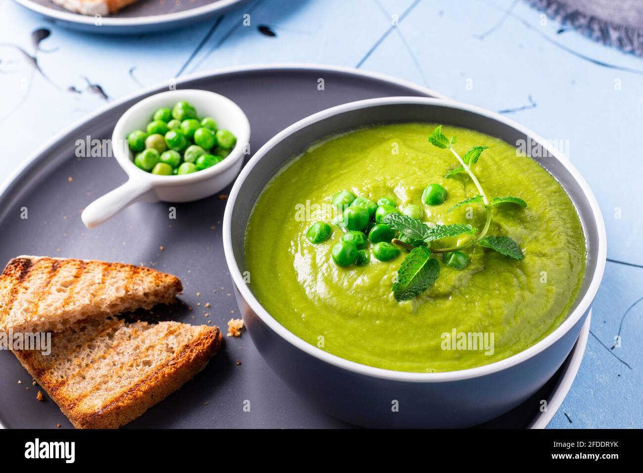 Fresh homemade peas cream soup with mint and toasted bread. Stock Photo