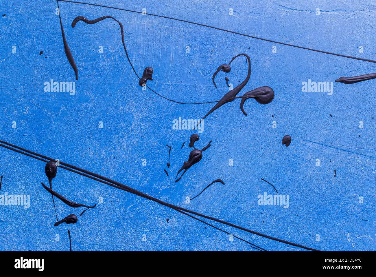 Concrete blue background with black painting of swirl, line and drops. Stock Photo
