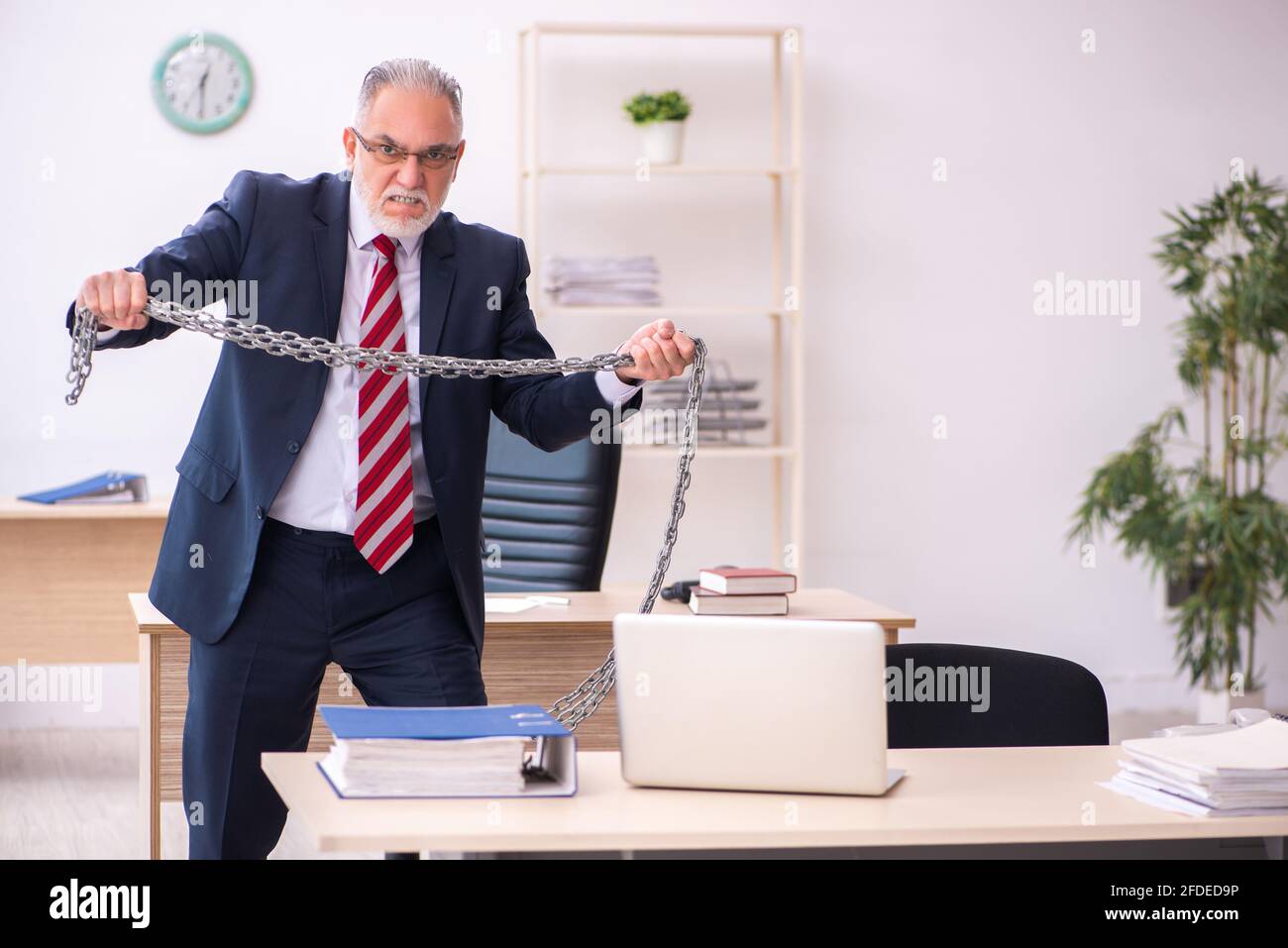 Old male employee holding chain at workplace Stock Photo - Alamy