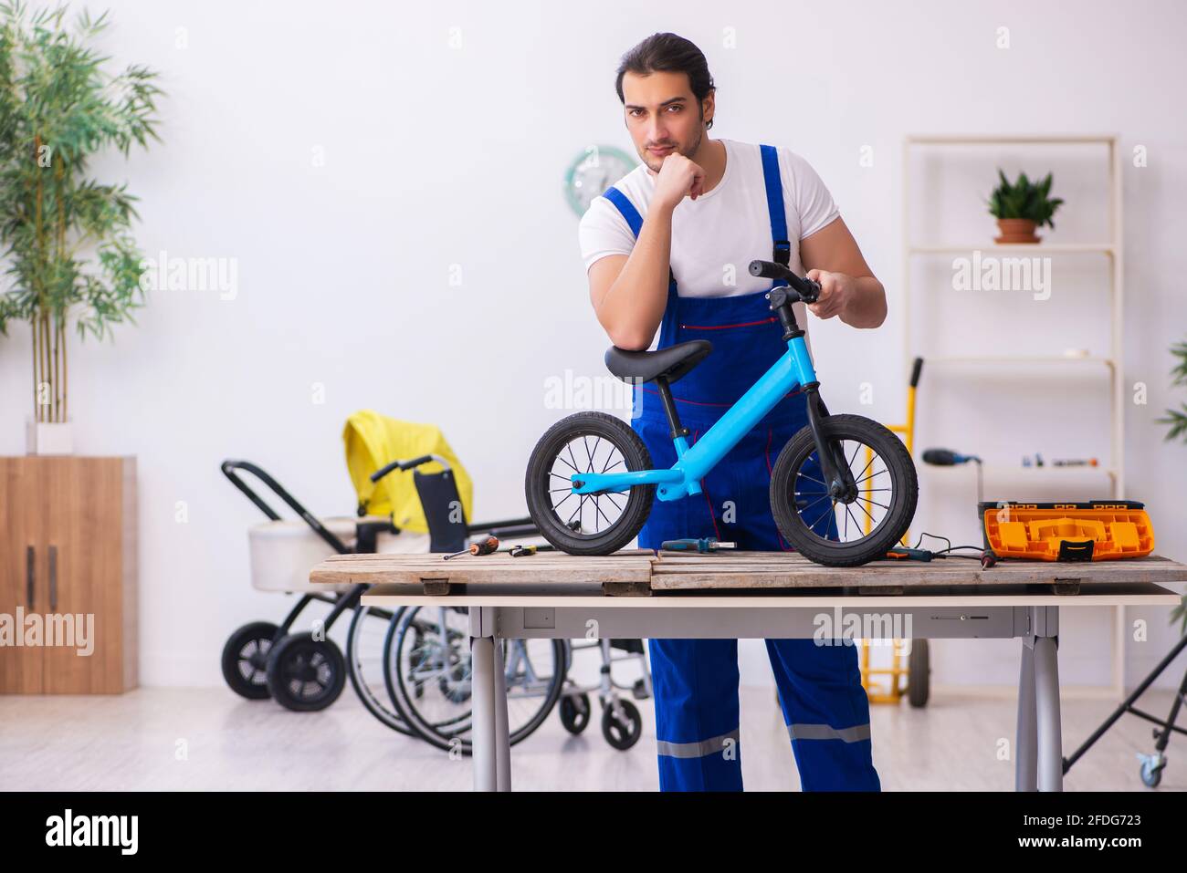 Young repairer repairing bike indoors Stock Photo - Alamy