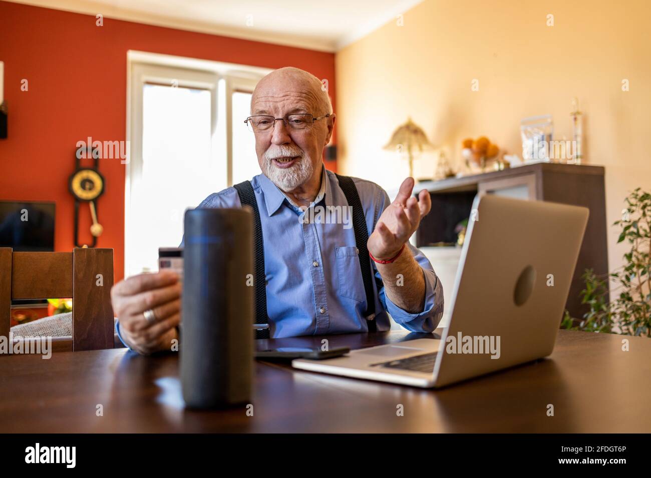 Senior man using Virtual Assistant at home Stock Photo