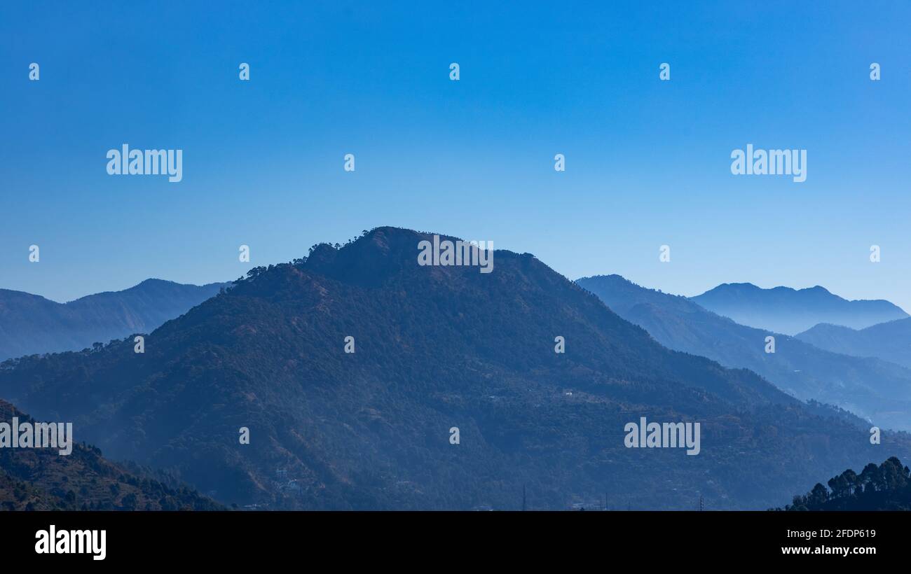 A panoramic view of silhouette of layers of mountains with fog in the ...