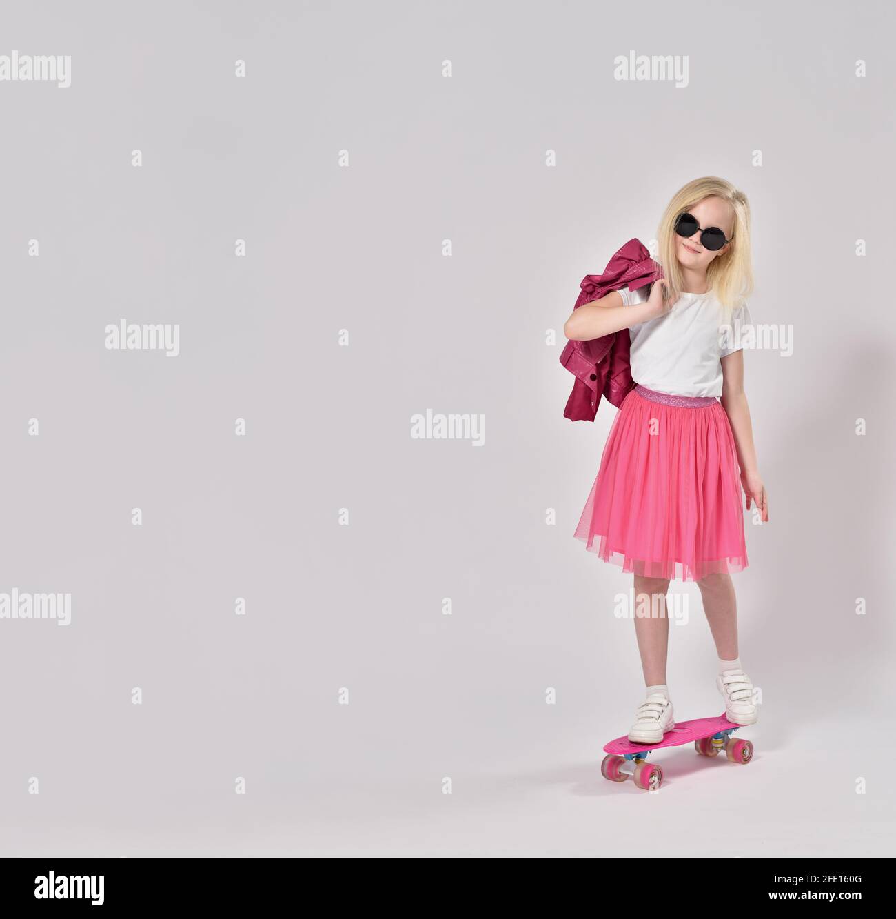 Teenage girl in pink clothes stands on skateboard Stock Photo Alamy