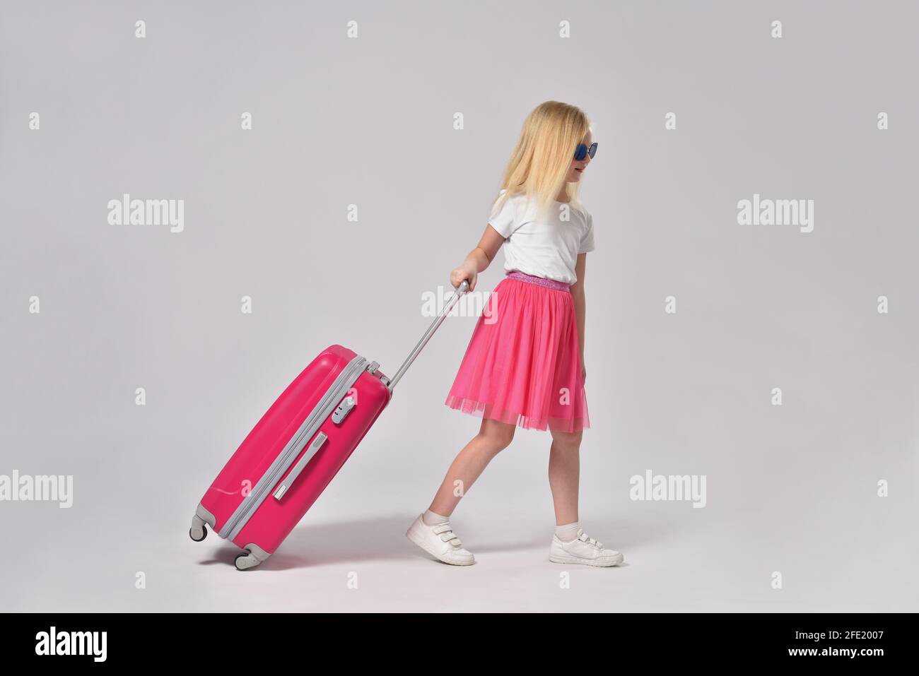 Teenage girl rolling pink suitcase Stock Photo Alamy