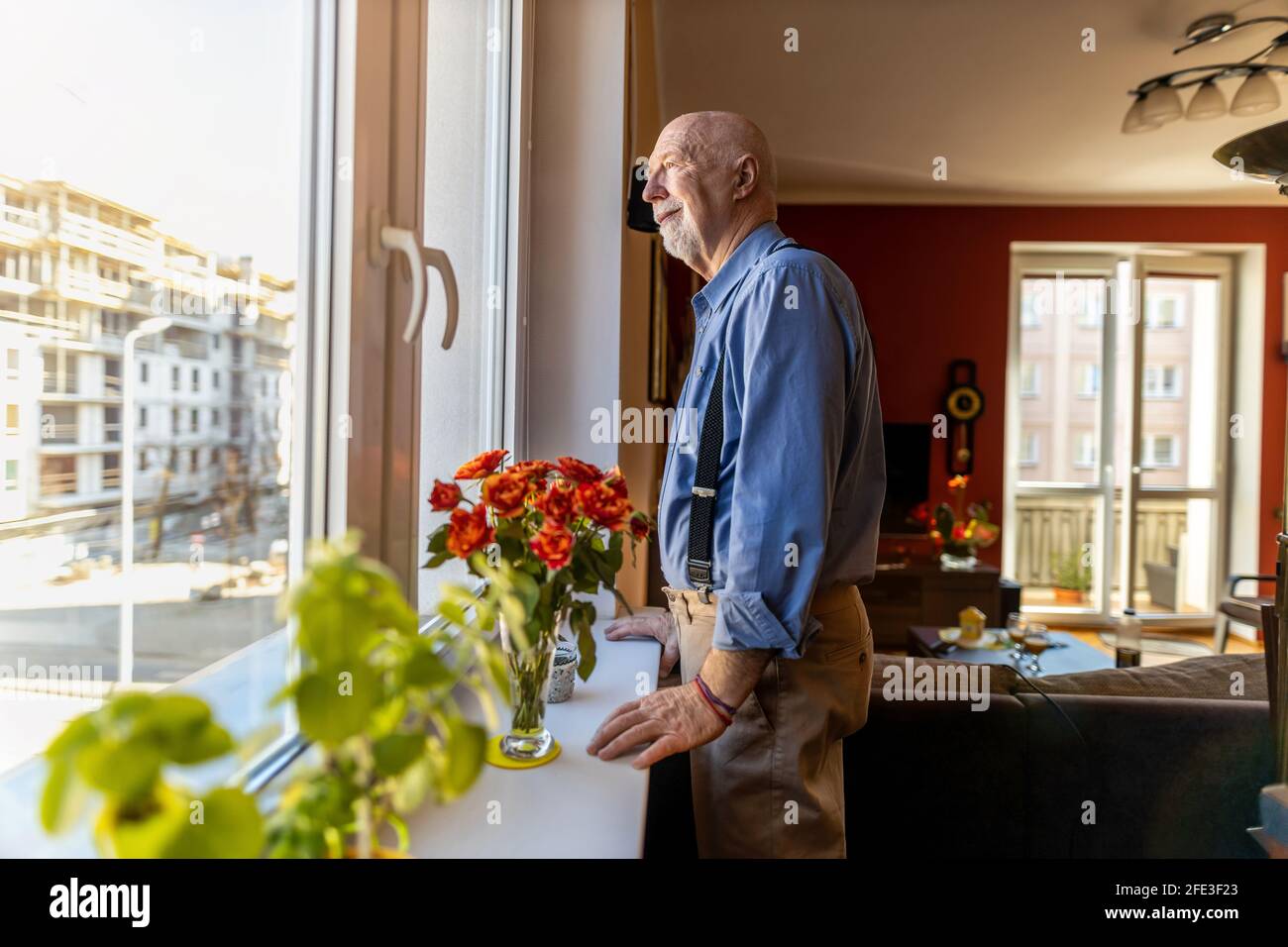 Senior Man Looking Through Window at Home Stock Photo