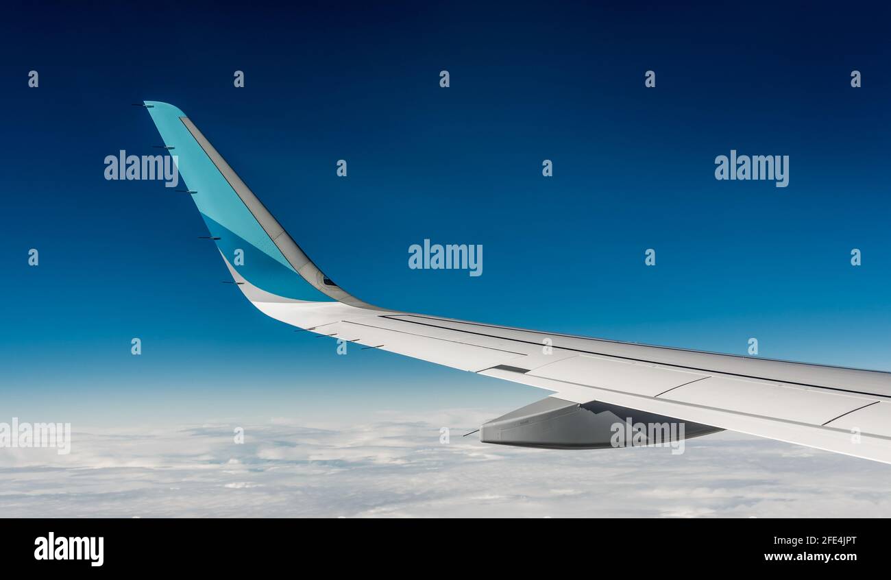 Wing of airplane. View from windows seat during aircraft flight. Blue sky with soft white clouds Stock Photo